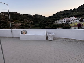Terraço no telhado com um banco branco e um vaso decorativo.