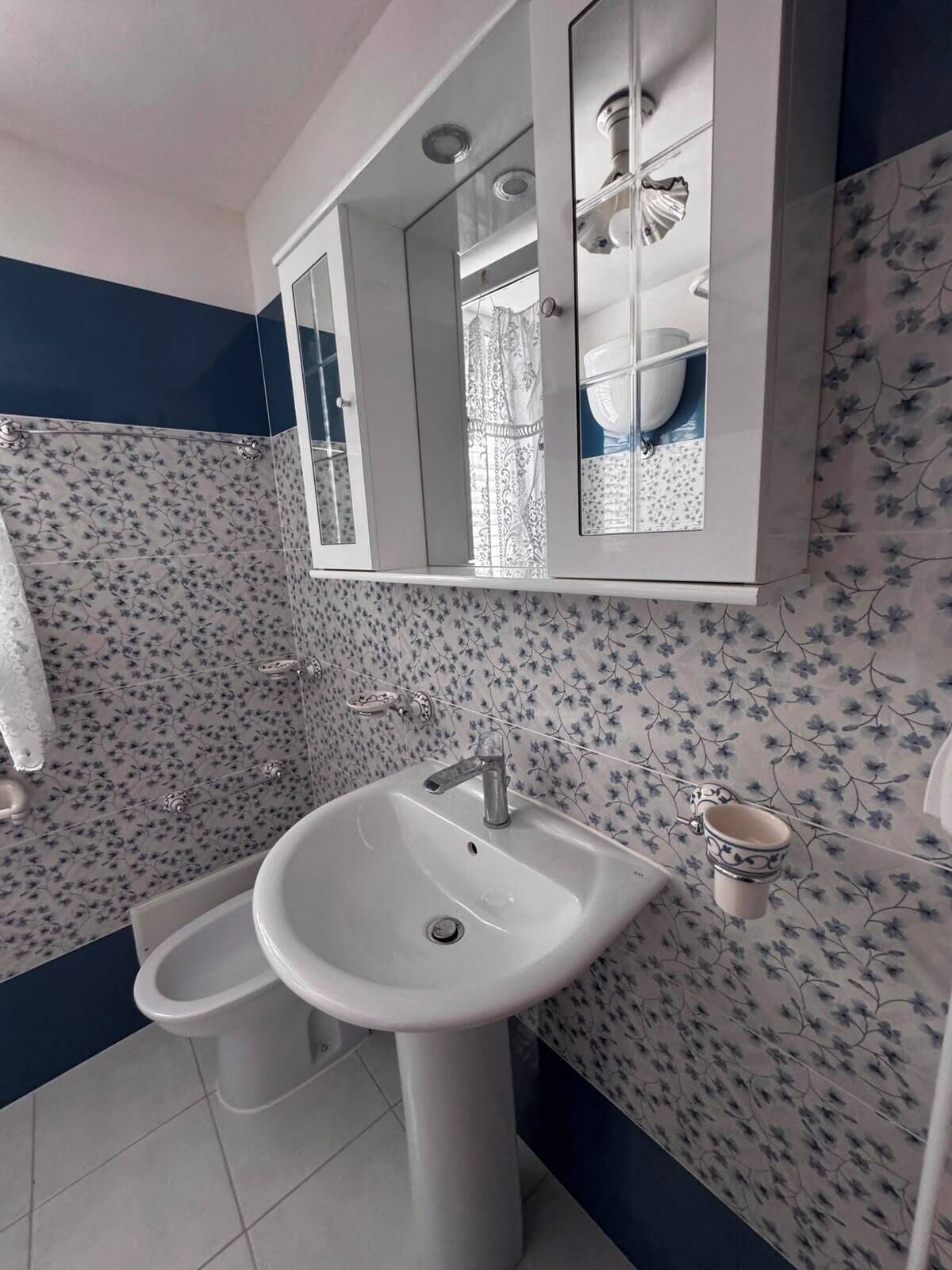 Un baño con lavamanos blanco, un espejo y un inodoro.