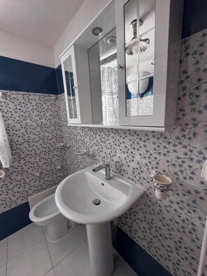 A bathroom with a white sink, a mirror, and a toilet. - Between the Sea and the Sky: Ponza - New Apartment (Ponza)