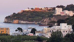 A coastal town with buildings on a hillside, a lighthouse, and boats in the water. - Between the Sea and the Sky: Ponza - New Apartment (Ponza)