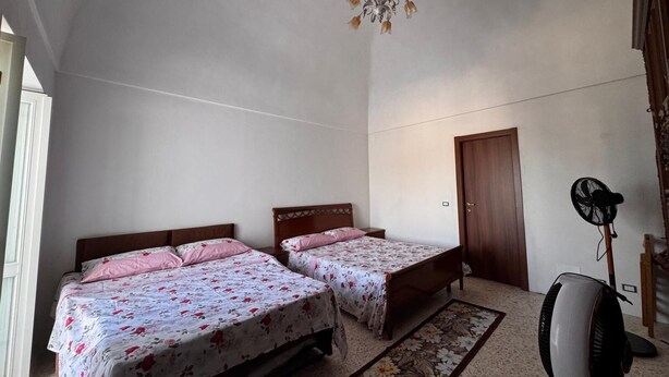 A bedroom with two beds, a ceiling fan, a door, and a window. - Between the Sea and the Sky: Ponza - New Apartment (Ponza)