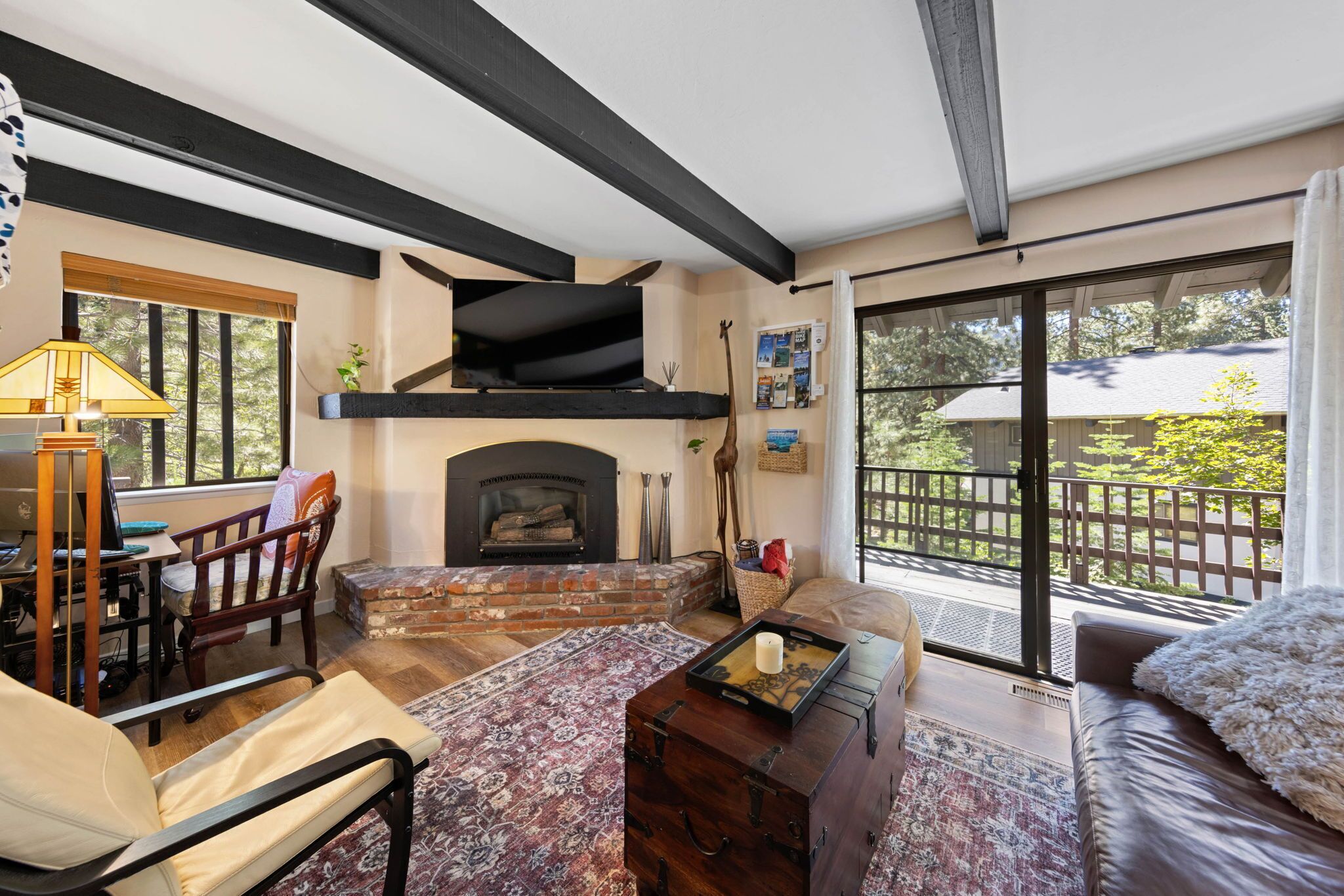 A cozy living room with a fireplace, a sofa, a coffee table, and a dining area with chairs.
