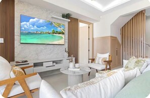 A modern living room with a flat-screen TV, comfortable seating, and a view of the outdoors. - The Hidden Pearl of Punta Cana in White Sands (Punta Cana)
