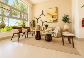 A modern living room with a large window, a sofa, a coffee table, and decorative items. - The Hidden Pearl of Punta Cana in White Sands (Punta Cana)