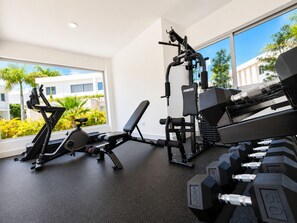 A gym with exercise equipment, including a treadmill, weight bench, and dumbbells. - The Hidden Pearl of Punta Cana in White Sands (Punta Cana)