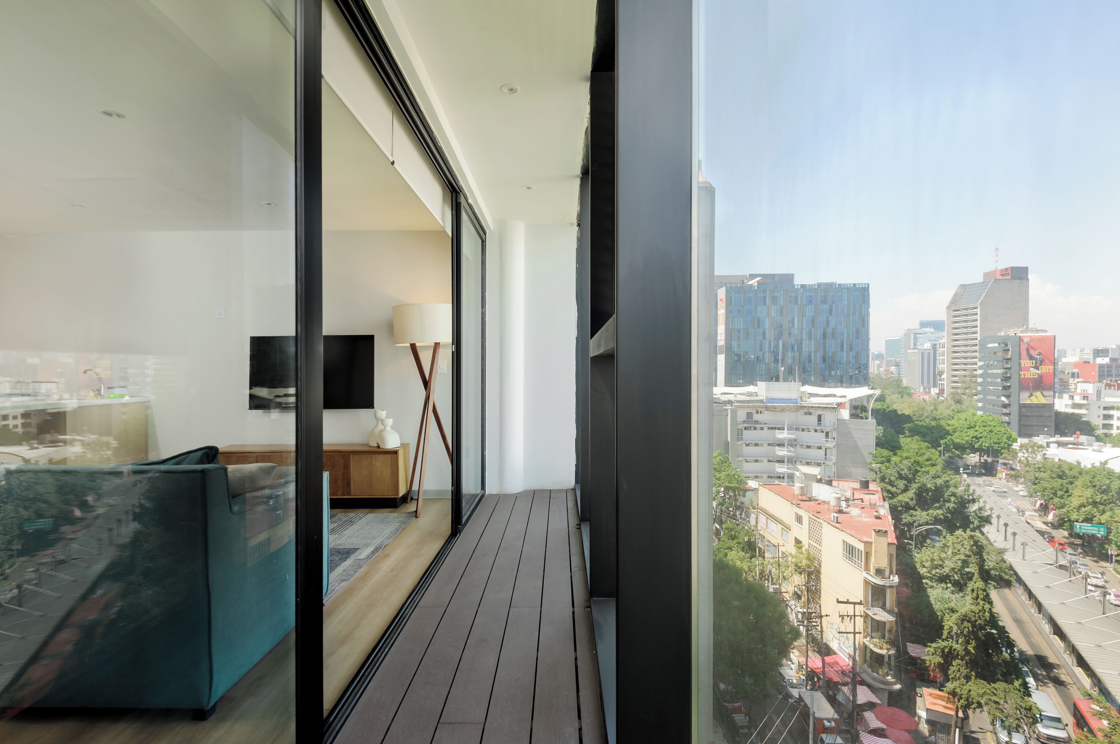 Un balcón con vista a la ciudad, un sofá, un televisor y una lámpara.