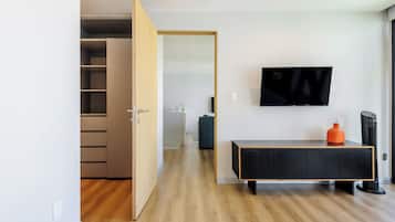 Una sala moderna con piso de madera, un mueble de entretenimiento negro, un televisor montado en la pared y un armario con puertas correderas.