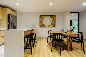 A modern kitchen with a central island, bar stools, and a dining table with chairs. - Insurgentes Roma Sur by Wynwood House (Ciudad de México)