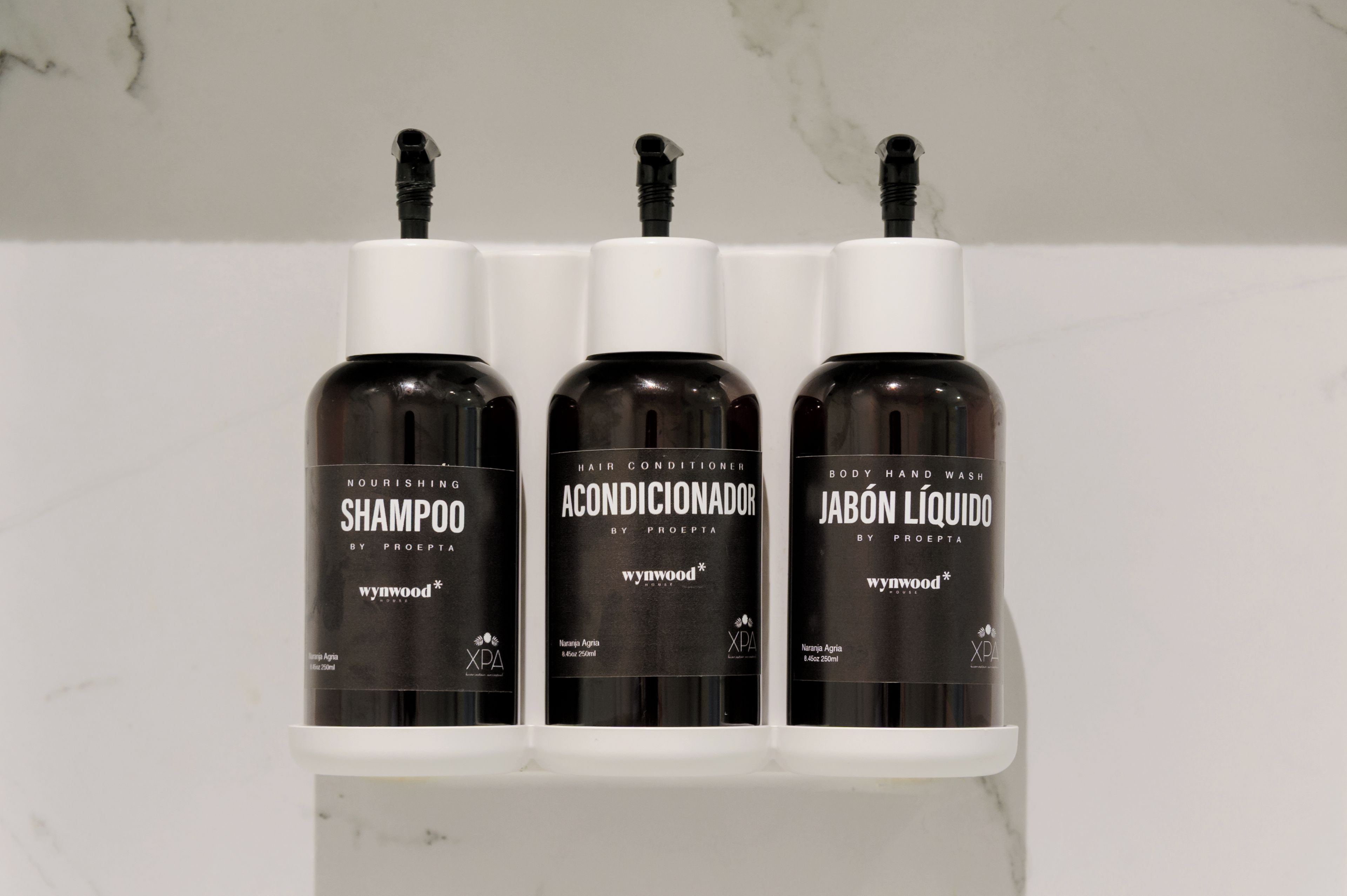 Three bottles of hair care products on a white shelf.