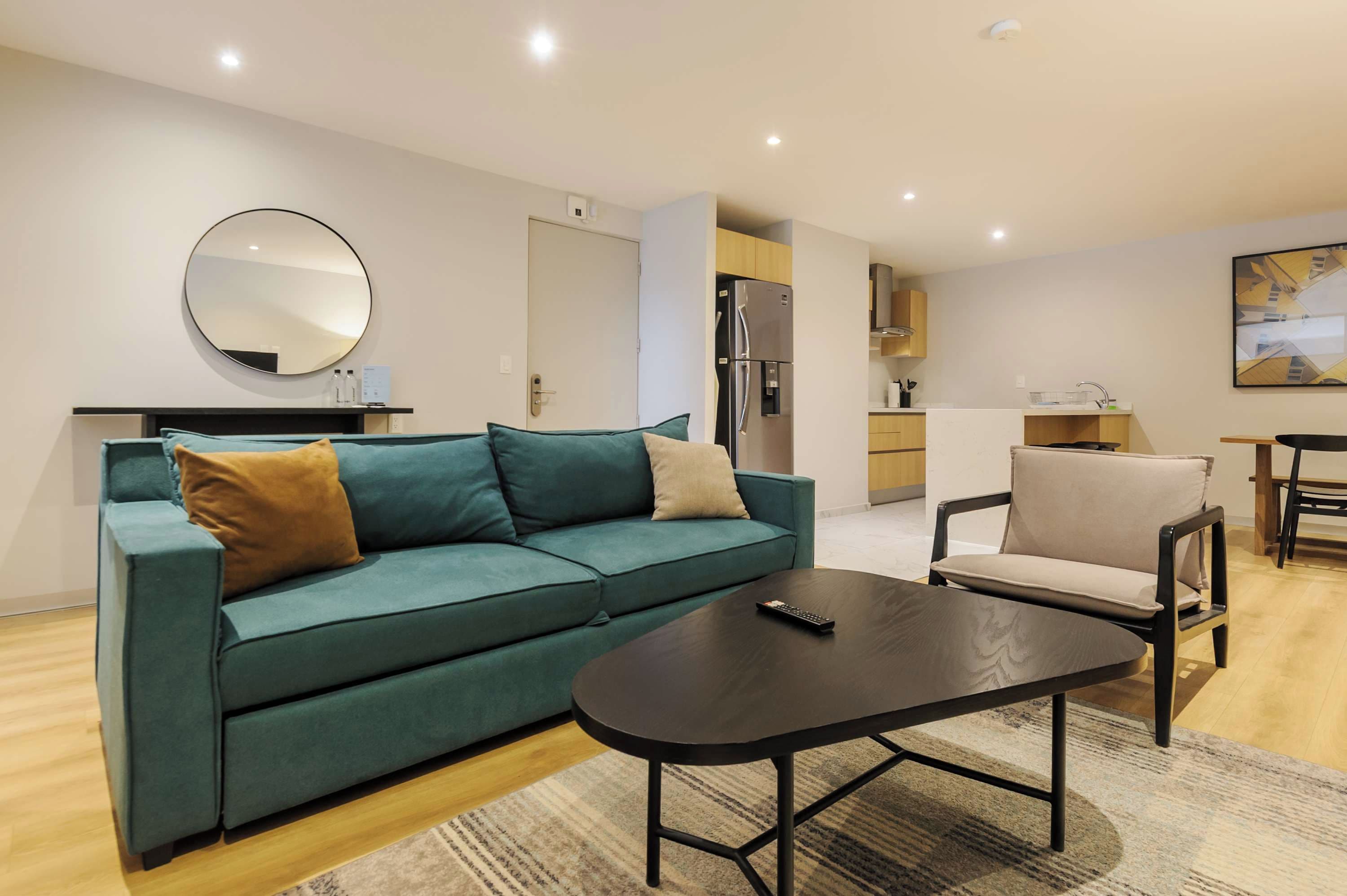 Ein modernes Wohnzimmer mit einer Couch, einem Couchtisch und einer Küchenzeile im Hintergrund.