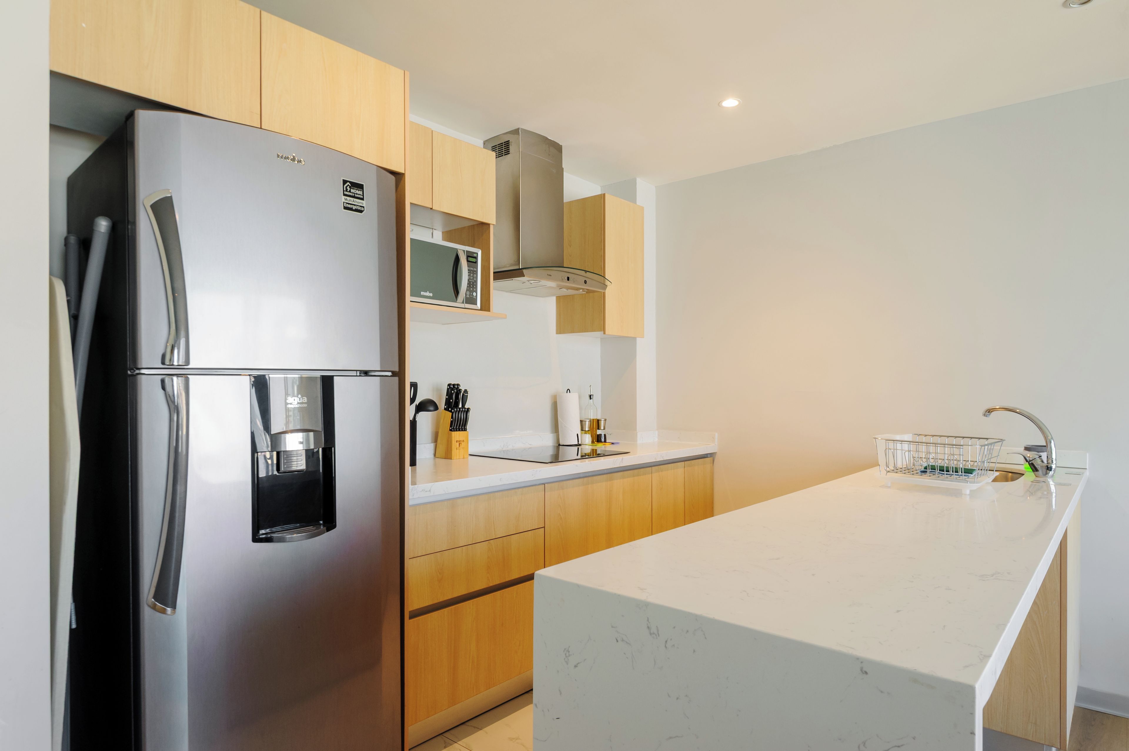 A modern kitchen with a stainless steel refrigerator, microwave, and a built-in water dispenser.
