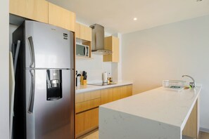 A modern kitchen with a stainless steel refrigerator, microwave, and a built-in water dispenser. - Insurgentes Roma Sur by Wynwood House (Ciudad de México)
