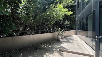 Um edifício moderno com fachada de vidro, um cachepot de concreto com planta em vaso e um espaço de pátio com ladrilhos.