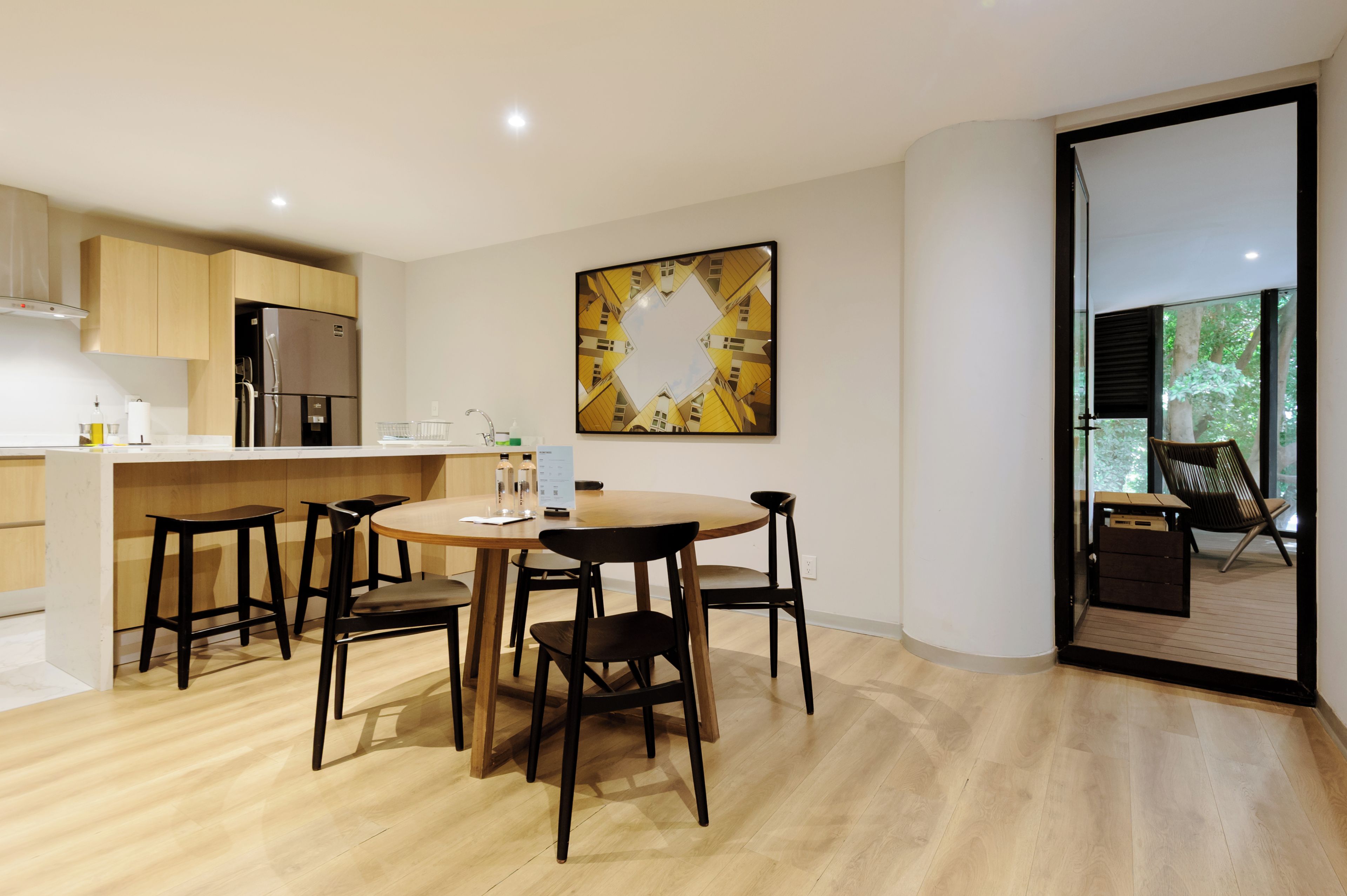 Eine moderne Küche mit Holzausstattung, einem Edelstahlkühlschrank und einem Essbereich mit rundem Tisch und vier Stühlen.