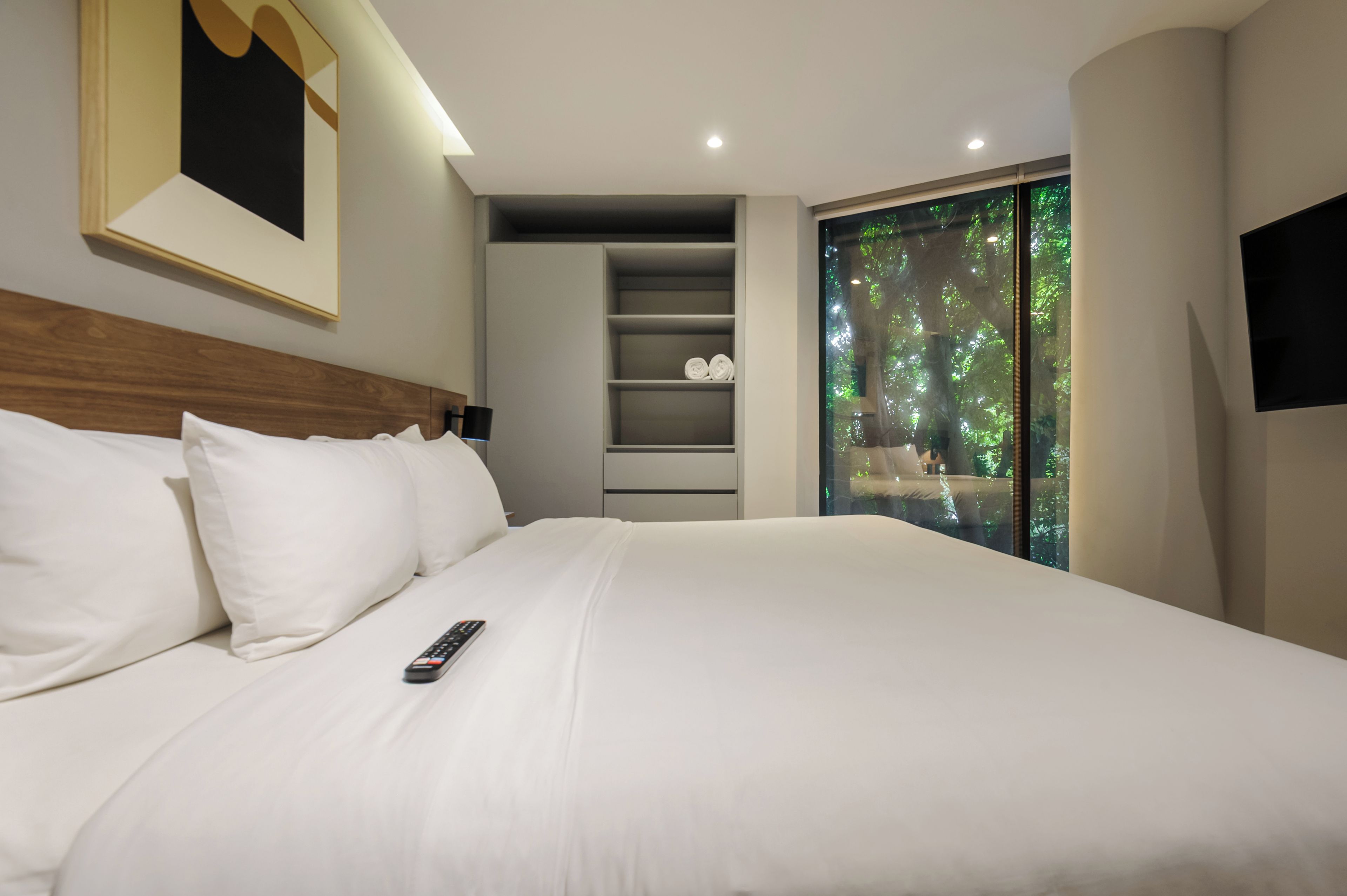 Cama bem arrumada com lençóis brancos e um controle remoto.
