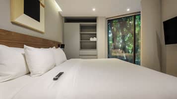 Cama bem arrumada com lençóis brancos e um controle remoto.