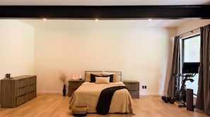 A bedroom with a bed, bedside tables, a wardrobe, a window with curtains, and a treadmill.