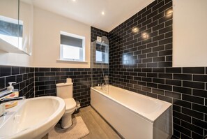 Ein modernes Badezimmer mit Toilette, Waschbecken und Badewanne.