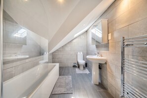 Ein modernes Badezimmer mit Badewanne, Waschbecken und Toilette.