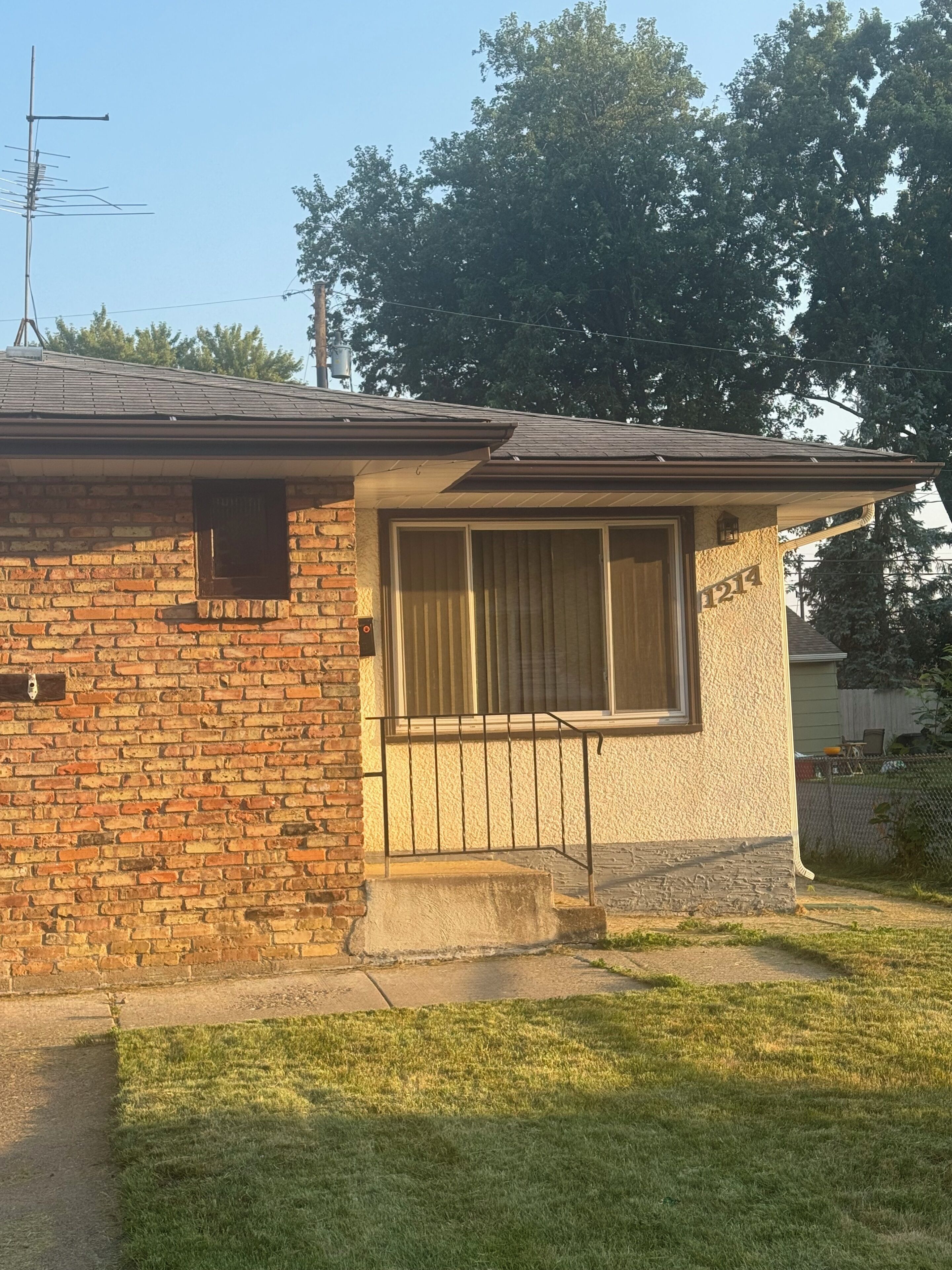 Una casa residencial con fachada de ladrillo, una ventana con persianas y un número de dirección visible.