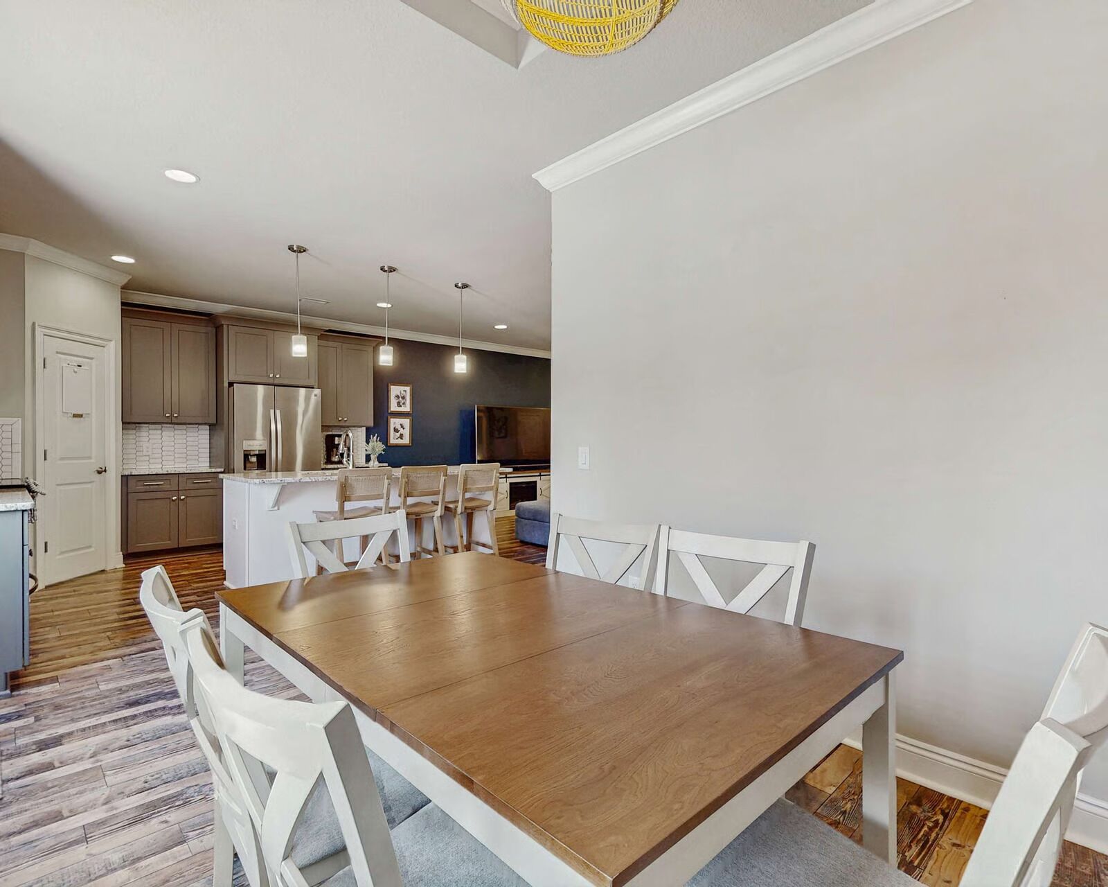A modern kitchen with white cabinets, a wooden dining table, and white chairs.