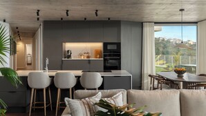 Et moderne køkken med en central ø, barstole og et spiseområde med udsigt.