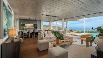 Een ruime woonkamer met een modern design, met een bank, salontafel en uitzicht op zee.