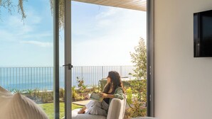En person læser en bog på en balkon med havudsigt.