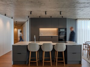 Eine moderne Küche mit einer zentralen Kochinsel, Barhocker und integrierten Geräten.