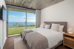 Ein Schlafzimmer mit einem großen Bett, einem Nachttisch, einer Lampe und Meerblick.