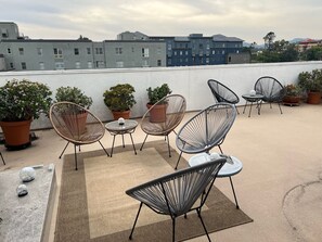 A rooftop terrace with outdoor seating and potted plants.