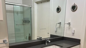 Ett modernt badrum med en stor spegel, ett handfat och en dusch med glasväggar.