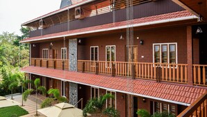 Een gebouw met twee verdiepingen, een balkon, een stenen pilaar en een overdekt patio met parasols.