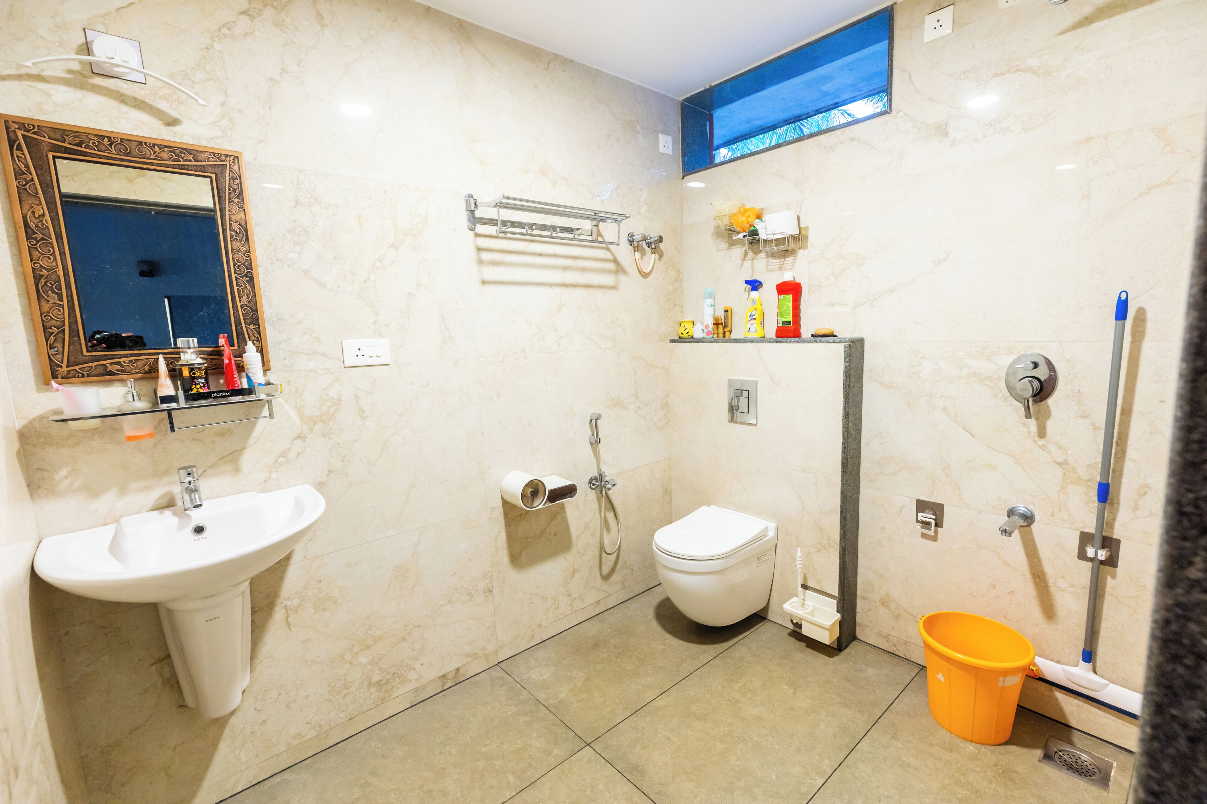 A bathroom with a sink, toilet, shower, and a mirror with a decorative frame.