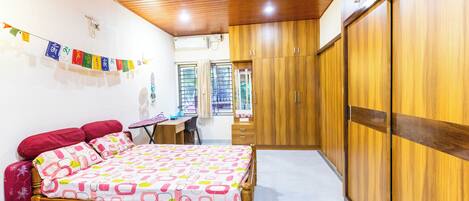 Une chambre à coucher avec un lit, une armoire en bois et un bureau avec une chaise.