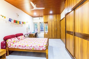 A bedroom with a bed, wooden wardrobe, and a desk with a chair.