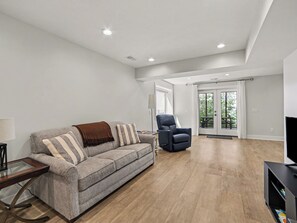 Un salon moderne avec un canapé gris, un fauteuil noir et un plancher en bois.