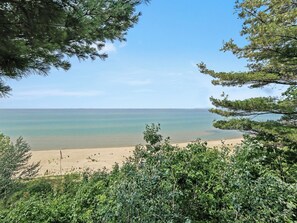 Une plage à l’eau claire et au rivage sablonneux, entourée d’une végétation luxuriante.