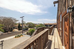 Een houten balkon met uitzicht op een straat en huizen.