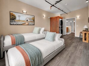 A hotel room with two beds, a painting on the wall, a washing machine, and a small table with a lamp. - OldTown Barnhouse 2Units Historic OldTown & Dining (San Diego)