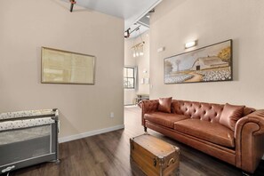 Un salon spacieux avec un canapé en cuir marron, une commode en bois et une grande reproduction d’un plan architectural encadrée au mur.