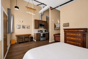 A hotel room with a bed, wooden furniture, a kitchenette, and a view of the outdoors. - OldTown Barnhouse 1BR Historic OldTown & Dining (San Diego)