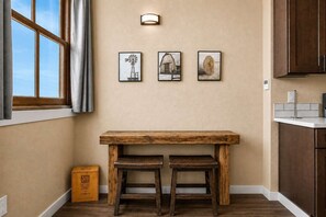 A kitchen with a wooden table and stools, a window with curtains, and three framed pictures on the wall. - OldTown Barnhouse 1BR Historic OldTown & Dining (San Diego)