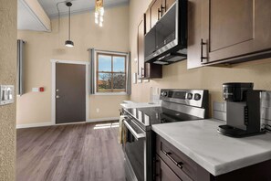 A modern kitchen with stainless steel appliances, a window with curtains, and a door. - OldTown Barnhouse 1BR Historic OldTown & Dining (San Diego)