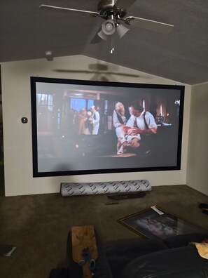 A television mounted on a wall with a ceiling fan above it.