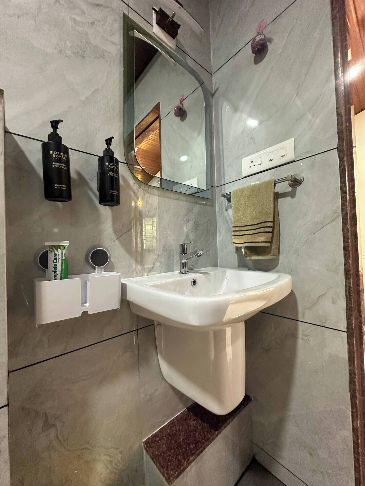 A bathroom with a white sink, a mirror, and toiletries on the wall.