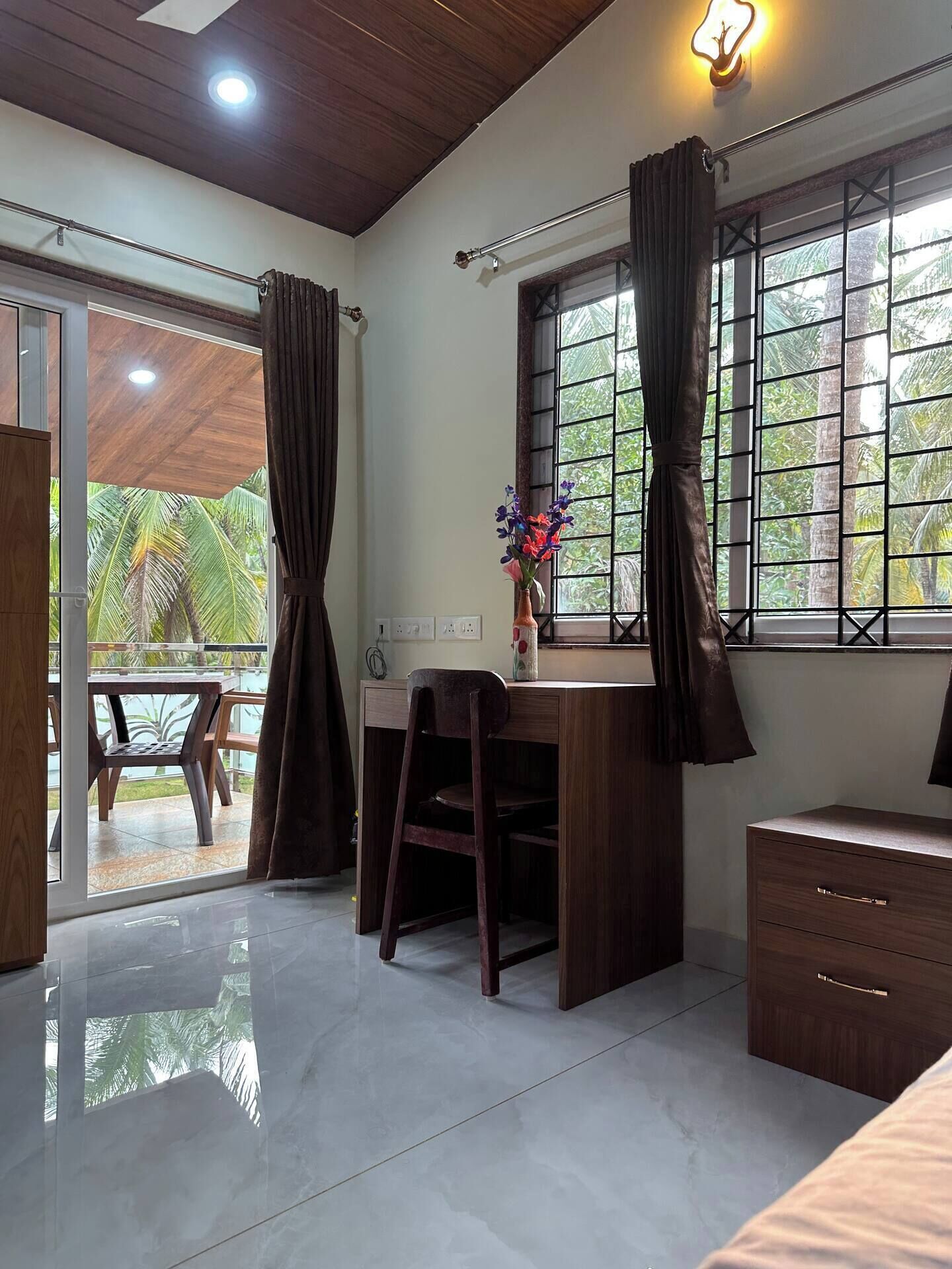 A room with a desk, chair, and a window with curtains.