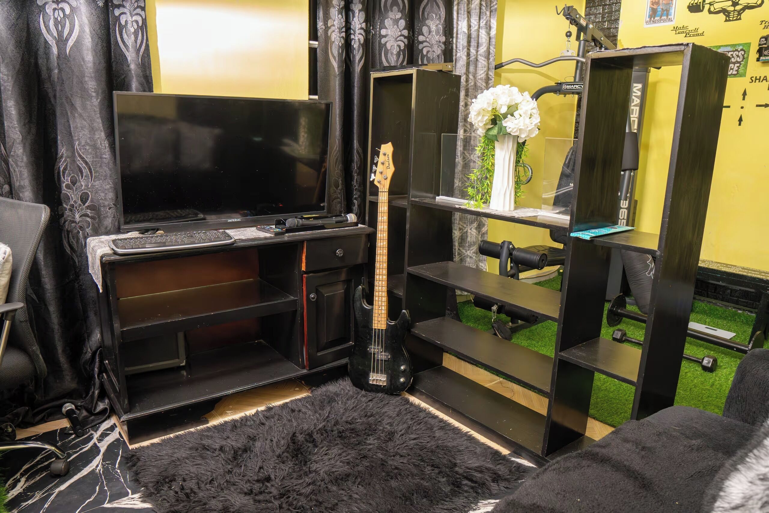 A living room with a black entertainment unit, a guitar, and a TV.