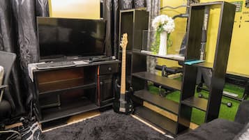 Una sala de estar con un mueble negro para entretenimiento, una guitarra y un televisor.
