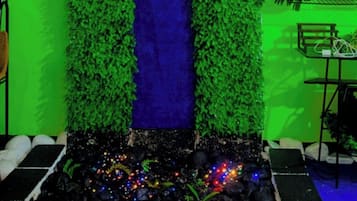Uma entrada decorada com um letreiro que diz 'Happy 28th Birthday Nick', folhagem verde e um recurso de cachoeira azul.